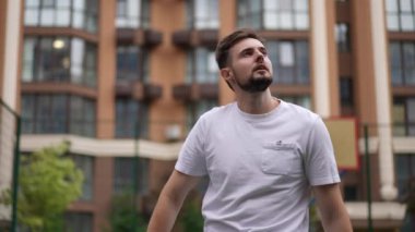 Kendine güvenen sporcunun portresi yavaş çekimde tenis topu servis etmeyi hedefliyor. Beyaz tenli yakışıklı genç adam raket kaldırırken kameralar açık havaya bakıyor.