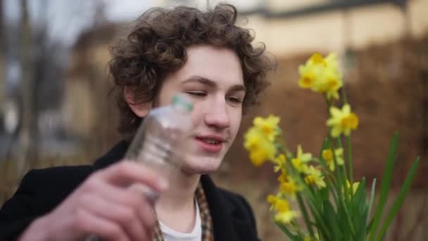 Retrato Sonriente Joven Relajado Vertiendo Agua Maceta Con Flor Amarilla — Vídeo de stock