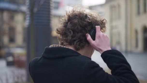 Kıvırcık Saçlı Kulaklık Takan Genç Adam Şehrin Sokaklarında Dans Etmeye — Stok video