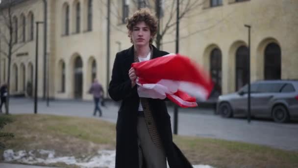 前视自信的男人伸展着加拿大国旗 看着站在室外的相机 骄傲的年轻人在城市街道上摆出国徽 — 图库视频影像