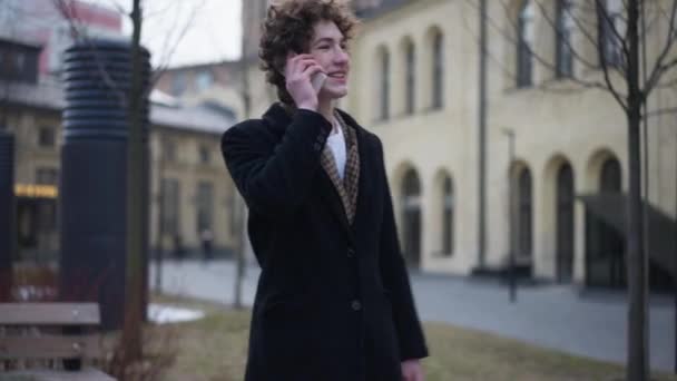 ライブカメラのズームとして電話で話す幸せな男の肖像画 都市部の路上で立っている自信に満ちた肯定的な白人男性の笑顔チャット — ストック動画
