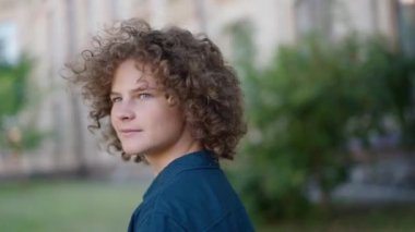 Beyaz, kıvırcık saçlı, açık havada ağır çekimde etrafa bakan sevimli bir çocuk. Çekici bir çocuğun hafta sonu eğlencesinin portresi. Çocukluk ve yaşam tarzı kavramı