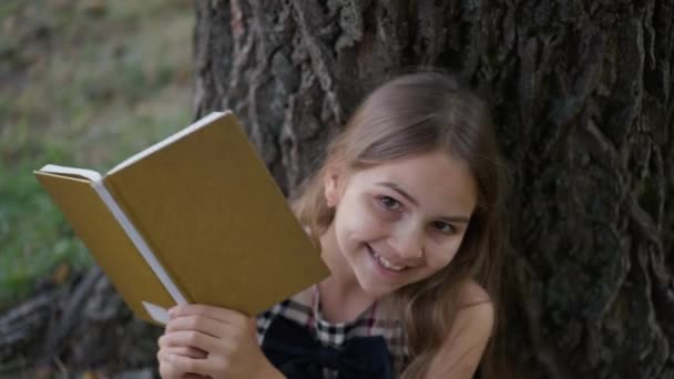 Χαρούμενη Έξυπνη Μαθήτρια Που Εμφανίζεται Πίσω Από Ένα Βιβλίο Χαμογελώντας — Αρχείο Βίντεο