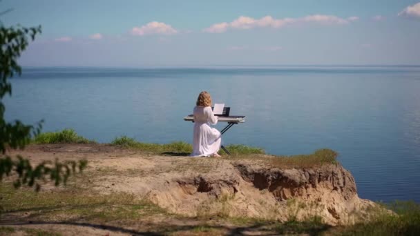 Uçurumda Piyano Sentezleyicisi Çalan Yetenekli Bir Kız Mavi Nehir Dalgalarının — Stok video