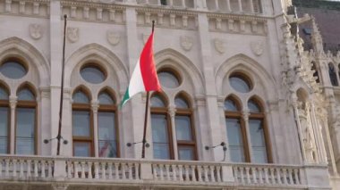 Budapeşte, Macaristan - 16 Mayıs 2022: güneşli bir günde Macaristan Parlamento Binası 'nda ulusal bayrak dalgalanıyor. Şehir merkezindeki hükümet kurumu