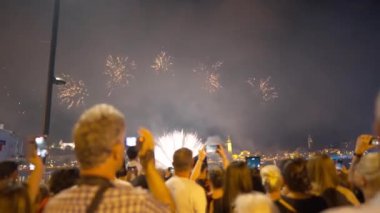 Budapeşte, Macaristan - 16 Mayıs 2022: Açık havada havai fişek çeken bir kalabalık. Akıllı telefonları olan bir grup erkek ve kadın tatilde uygulamalarla video kaydediyor.