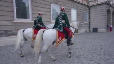 Budapeşte, Macaristan - 16 Mayıs 2022: Antik şehir caddesinde atları geçen iki Macar süvarisi. Kendine güveni tam polisler, açık havada eski üniformalı hayvanlara biniyorlar.