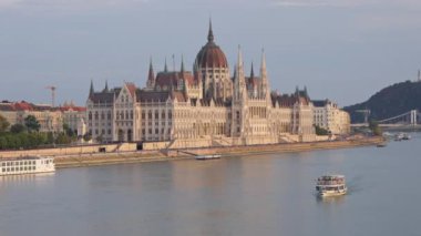 Budapeşte, Macaristan - 16 Mayıs 2022 Macaristan Parlamento Binası feribotla gün ışığında açıldı. Gotik stil antik şehir inşaatı ve gemi güneş ışığı altında bahar günü