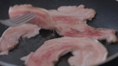Yakından erkek eli pastırmayı çatalla kızartma tavasında dilimliyor. Tanımlanamayan beyaz adam evde mutfakta lezzetli et pişiriyor. Mutfak ve yemek konsepti