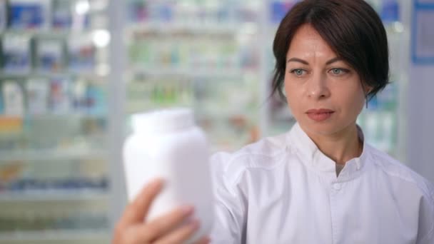 Closeup Concentrated Woman Reading Bottle Pills Standing Drugstore Right Portrait — Stock Video