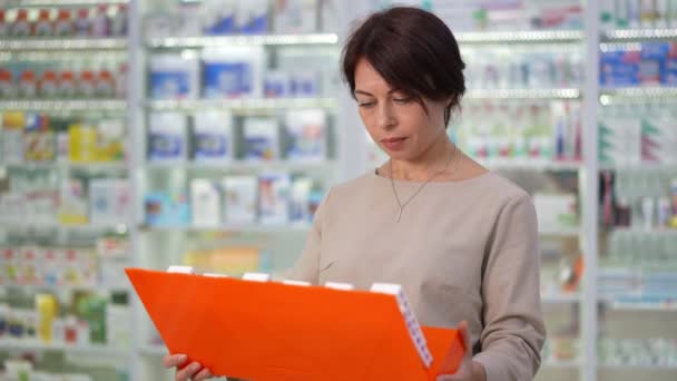 认真集中的白人妇女在药物思维中选择药物 一组药物陈列在药店的室内 是经过深思熟虑的专注买家的中景肖像画 慢动作 — 图库视频影像