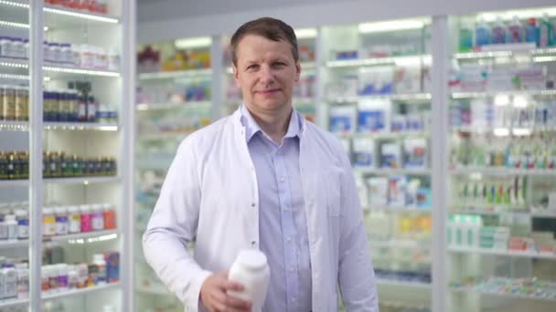 Zoom Retrato Farmacêutico Masculino Sorridente Confiante Que Estica Garrafa Complexa — Vídeo de Stock