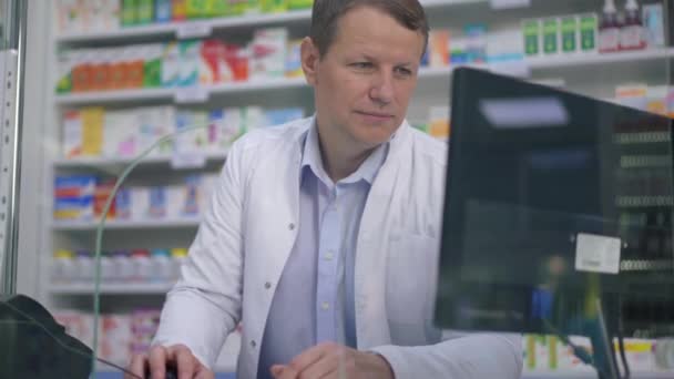 Farmacéutico Masculino Inteligente Positivo Usando Ordenador Sentado Cajero Automático Farmacia — Vídeo de stock