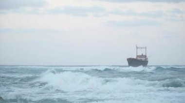 Akdeniz 'in fırtınalı dalgaları bulutlu bir günde sağda gemi enkazları var. Geniş çaplı çalkantılı su ve Kıbrıs 'taki açık hava teknesi harap oldu. Doğa ve hava durumu