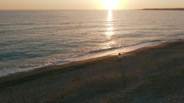 Akdeniz 'de altın gün batımında sahilde tanınmayan bir kadın akıllı telefon uygulaması ile fotoğraf çekiyor. Kafkas kadın turist Kıbrıs 'ta tatil yapıyor