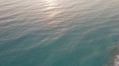 Kıbrıs 'ta açık havada güneş ışığında deniz yeşili su. Akdeniz deniz dalgalarının gün batımında güneş ışınlarında uçuşan hava aracı görüntüsü