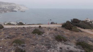 Ekstrem geniş açı, peri kostümlü beyaz kadın okyanus kayalıklarında keman çalarak kamerayı çeviriyor. Yetenekli yaratıcı sanatçı bulutlu bir günde Akdeniz 'de müziğin keyfini çıkarıyor.