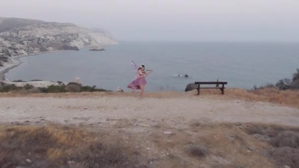 鼓手从穿着童话般服装 在悬崖上拉小提琴的天才女子手中冲向大海 在塞浦路斯地中海欣赏魔术音乐的高加索女音乐家的全景肖像 — 图库视频影像