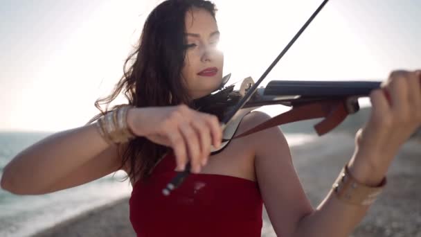 一个自信的女人在海滨的阳光下小提琴演奏 在地中海海滨慢镜头中表演音乐的天才白种人女士的画像 — 图库视频影像