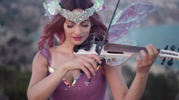 有才华的笑脸的女人穿着童话般的衣服 微笑着拉小提琴 看着镜头 积极自信的白人女士在户外表演 音乐和生活方式概念 — 图库视频影像
