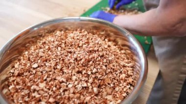 Yakın plan kasede doğranmış et parçaları ve masa üzerinde daha fazla kesen beyaz kadın elleri var. Yüksek açılı profesyonel aşçı restoranın mutfağında çalışıyor. Yavaş çekim