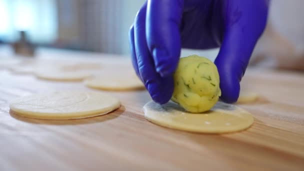 把土豆球放在木制桌子上的圆形面团上 无法辨认的白人女厨师戴着手套 在厨房里准备美味的传统乌克兰饺子 — 图库视频影像