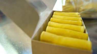 Lezzetli gözlemeler, karton kutuyla doldurulmuş beyaz kadın elleri ve eldiven kapama paketi. Tanınmayan bir kadın ağır çekimde paket servisi hazırlıyor.