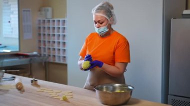 Kendine güvenen kadın aşçının portresi patates köftesi yapıyor. Lokanta mutfağındaki ahşap masaya hamur parçaları yerleştiriyor. Profesyonel beyaz kadın içeride lezzetli yemekler pişiriyor.