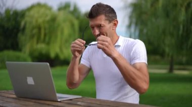 Yaz parkında dizüstü bilgisayarla oturup ağır çekimde gözlük takan zeki yakışıklı bir adam. Açık havada çalışan, kendinden emin, Kafkasyalı, serbest bir beyazın portresi. Yaşam dengesi kavramı