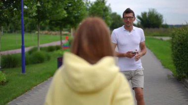İzleme görüntüsü bulanık beyaz bir genç kadının parkta neşeli yetişkin bir adamla buluşmasını sağladı. Gülümseyen mutlu adamın portresi yavaş çekimde arkadaşınla konuşuyor.