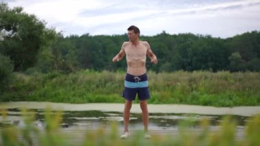 Kafkas sporcusunun geniş açılı portresi ısınıyor ve ağır çekimde dışarı bakıyor. Yakışıklı, kendine güvenen bir adam göl kıyısında parkta kaslarını esnetiyor. Spor ve yaşam tarzı