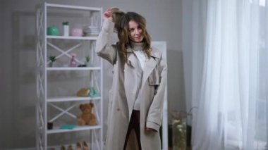 Kendine güveni tam, şık giyinmiş, şapkasını takmış, içeride kameraya bakan çekici bir kadın. Beyaz tenli güzel bir kadının oturma odasında poz verirken geniş açılı bir zaman dilimi portresi.