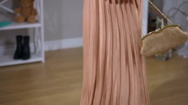 Zarif, ince, şık giyimli, yüksek topuklu, çantalı, kapalı mekanda gezen genç bir kadın. Beyaz bir kadının portresi. Gülümseyen bir kadın. Kamera yukarı aşağı hareket ederken gülümsüyor.