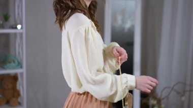 Canlı kamera, içeride kıyafet deneyen zayıf, kendine güvenen bir kadına doğru ilerliyor. Evdeki oturma odasında mutlu, beyaz, şık bir bayan.