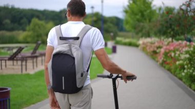 Canlı kamera, yavaş çekimde Scooter 'la yürüyen rahat, kendine güvenen adamı takip ediyor. Arka plan takibi, beyaz adamın sırt çantasıyla dışarıda dolaşırken görüntüsünü yakaladı.