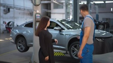 Minnettar, genç bir kadın otomobil istasyonundaki adamla el sıkışırken gülümsüyor ve ağır çekimde ayrılıyor. Minnettar beyaz kadın müşterinin portresi. İçeride uzman araba tamircisiyle tatmin olmuş.