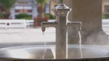 Açık havada güneşli bir günde sıcak termal pınarlı metal musluk. Çek Cumhuriyeti 'nin Karlovy Vary kentindeki sağlık merkezine yakın çekim ekipmanları
