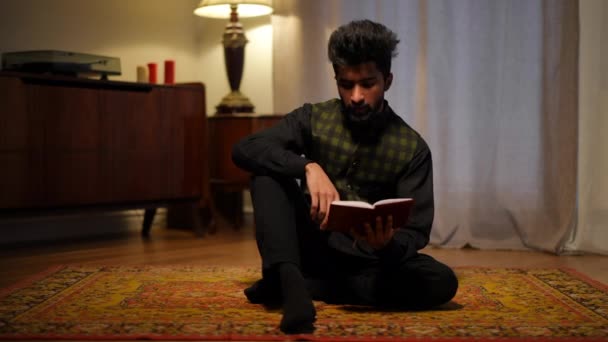 Szerokie Ujęcie Młodego Człowieka Bliskiego Wschodu Czytającego Koran Siedzącego Salonie — Wideo stockowe
