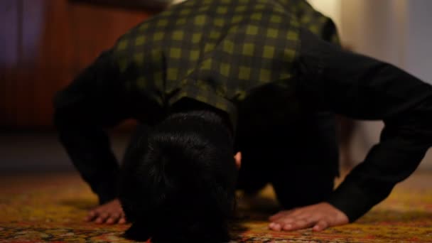 在室内地毯上鞠躬的穆斯林男子的特写 无法辨认的中东年轻宗教人士在斋月的客厅里举行宗教仪式 — 图库视频影像
