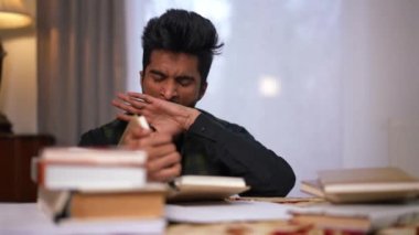 Orta Doğu 'dan yorgun, yetişkin bir erkek öğrenci masada uyukluyor. Evde kitap okuyan yorgun, çalışkan, genç ve yakışıklı adamın portresini büyüt.