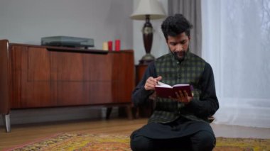 Oturma odasında dizlerinin üzerine çöküp Kuran okuyan, dua eden, tüküren ve kitabı kapayan genç Müslüman bir adam. Ramazan 'da kendinden emin Orta Doğulu inananın geniş açılı portresi