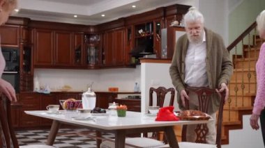 Oturma odasındaki yemek masasında oturan birkaç eski kıdemli arkadaş. Mutlu olumlu beyaz erkek ve kadınlar hafta sonu gülümseme toplantısı hakkında konuşuyor.