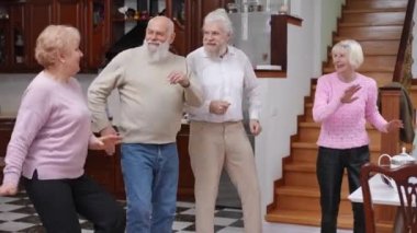Oturma odasında son sınıf öğrencilerinin neşeli dansları. Olumlu aktif Kafkasyalı karı ve kocalar dans ederken eğleniyorlar.