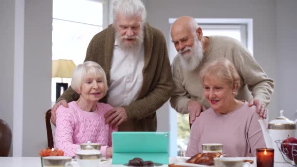 快乐的白种人老朋友坐在室内与数码平板电脑聊天 在客厅里微笑的男女在线聊天的人物形象 — 图库视频影像