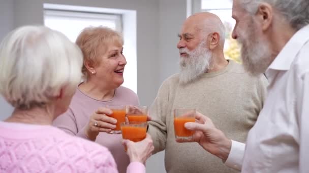 Gut Gelaunte Rentner Stoßen Mit Klingenden Saftgläsern Und Trinken Drinnen — Stockvideo