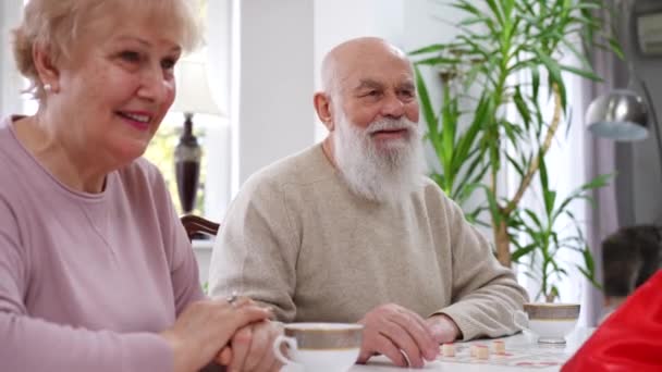 快乐的老夫妻和朋友在客厅里玩桌上游戏 积极的白种人微笑的老年男女在室内享受休闲 — 图库视频影像
