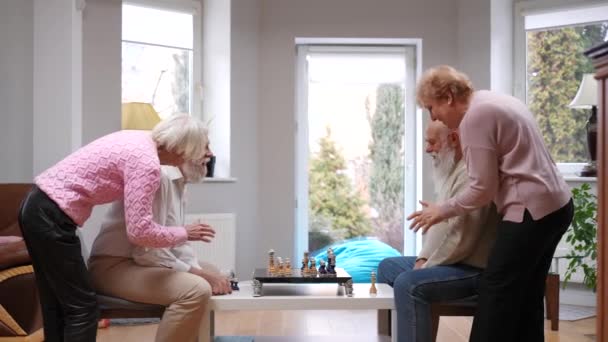 Neşeli Yaşlı Kadınlar Konsantre Olup Satranç Oynayan Erkeklere Tavsiyelerde Bulunuyor — Stok video