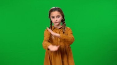 Kafası titremeyen, krom anahtar arka plandaki kameraya bakan ciddi bir beyaz kız. Yeşil ekranda poz veren kendine güvensiz bir gencin ön manzara portresi.