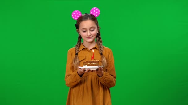 肯定漂亮的少女与一块生日蛋糕许愿吹灭蜡烛看着相机 微笑着自信的白人青少年在绿屏背景下庆祝节日 — 图库视频影像