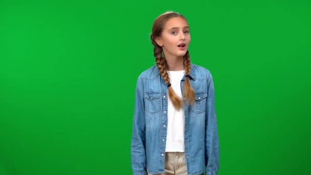 少女保持着沉默的姿态 用手指捂住嘴唇 看着站在绿色屏幕上的相机 高加索青少年在彩色背景下摆姿势的前视图肖像 — 图库视频影像